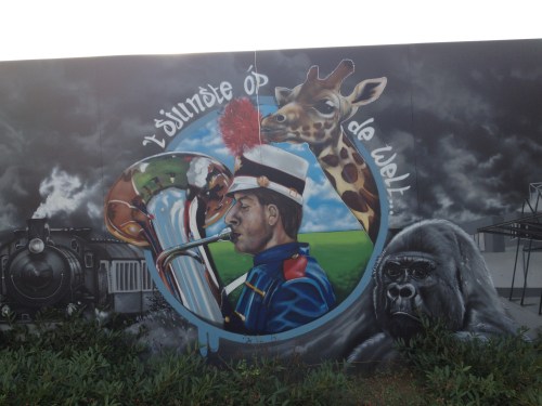 Een lelijke grijze muur waar ooit een prachtig groot huis heeft gestaan wordt opgeleukt door lokaal talent. Er zit muziek in ons dorp.