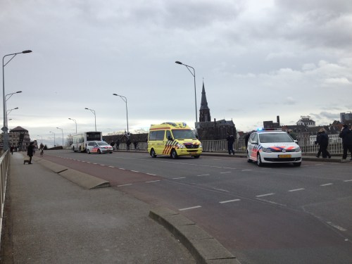 Donkere wolken boven de brug. Bus en brommer met elkaar in aanraking. Bus wint.