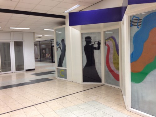 Lege gangen, opgeleukt met tekeningen op voormalige etalages. Muziek verstomd.