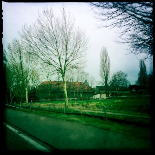 Per auto naar huis. Oude boerderijen verscholen in groen.