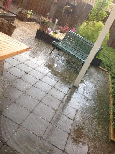 Een wolkbreuk die een klein zwembad in onze tuin laat ontstaan.