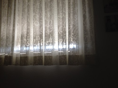 De zon speelt met de motieven in de gordijnen.